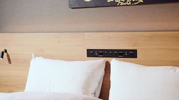 Habitación de hotel con cabecera de madera, regleta con varios enchufes y una obra de arte colgada en la pared.