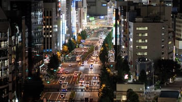 A nighttime cityscape with a busy intersection, illuminated buildings, and a pedestrian bridge.