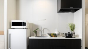 A compact kitchen with a white refrigerator, a microwave, a sink, and black cabinets. - MIMARU Tokyo Shinjuku West (Tokyo)