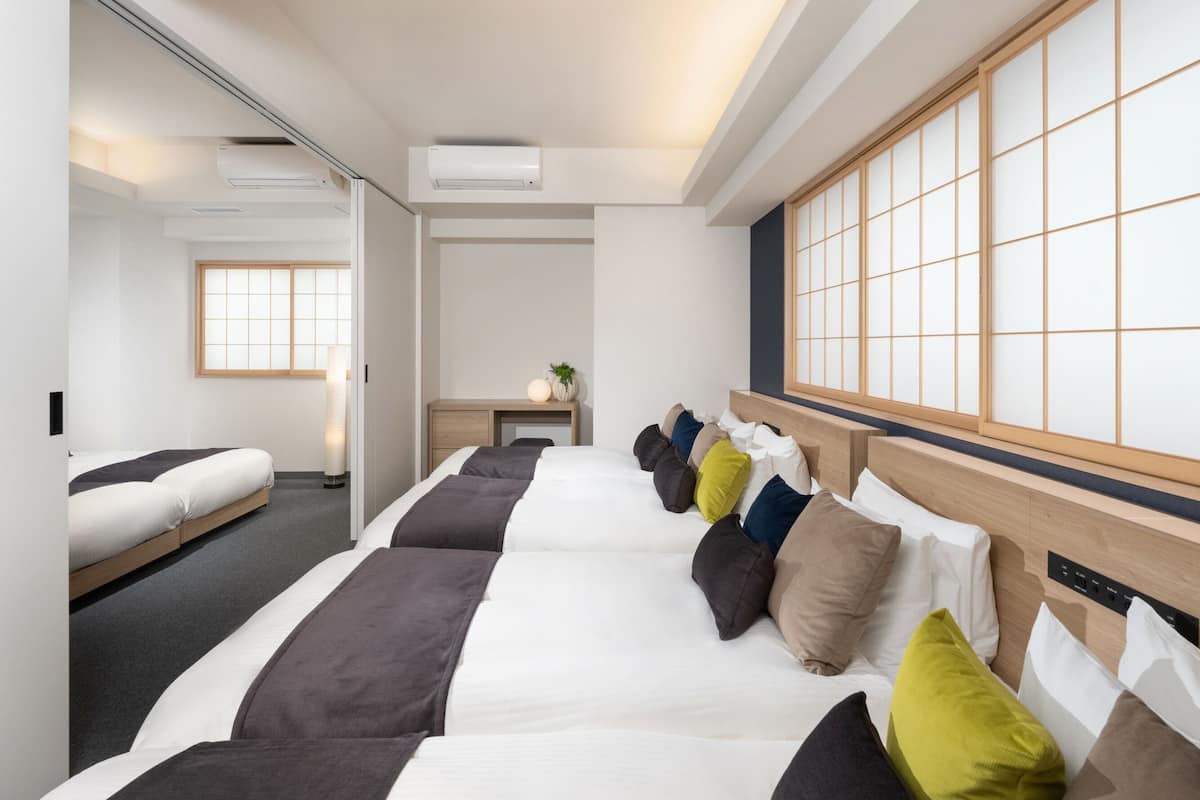 Ein Hotelzimmer mit einem großen Bett, einem Schreibtisch und einem traditionellen japanischen Shoji-Bildschirm.