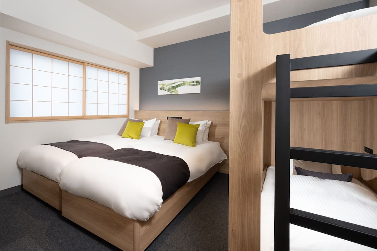 Ein modernes Hotelzimmer mit Stockbett, großem Fenster und minimalistischem Design.