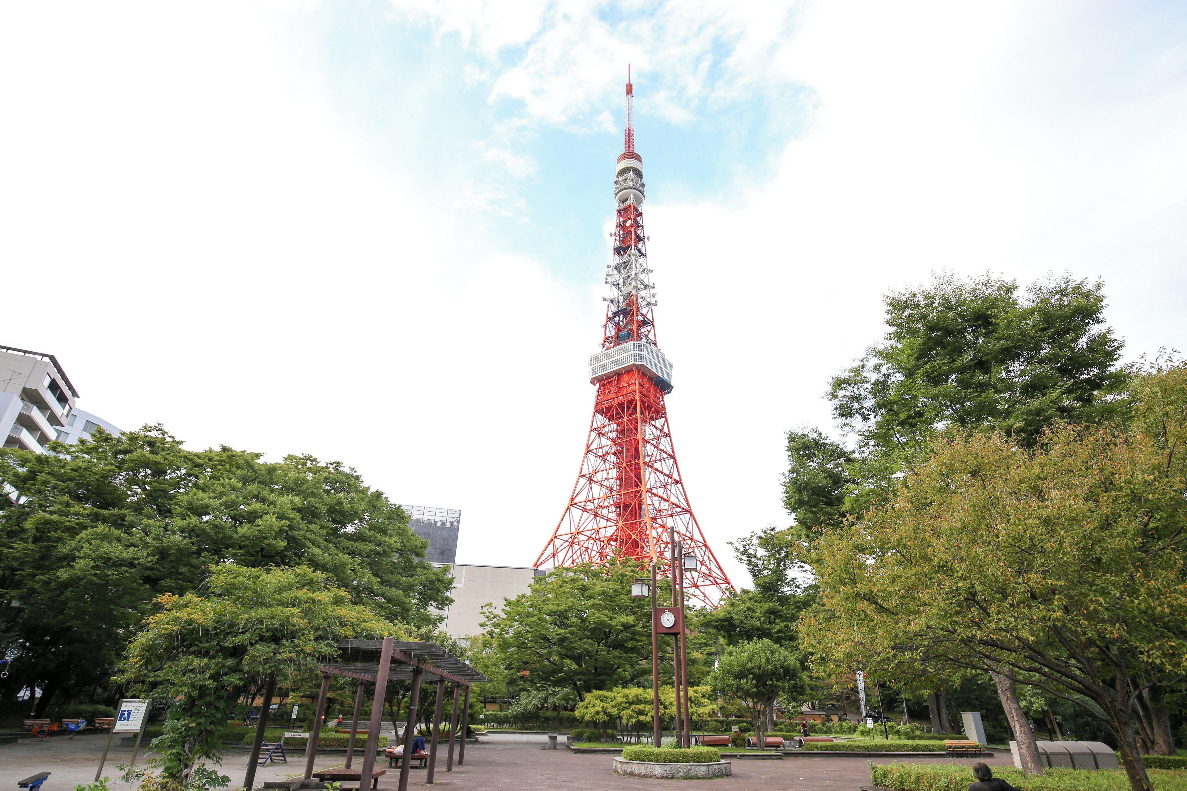 Ein roter Turm in einem Park mit Bänken und Bäumen.