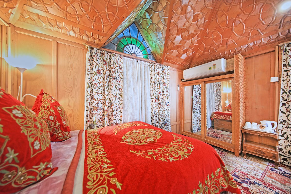 Una habitación tradicional con una cama grande, cortinas decoradas y techo de madera.