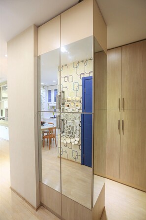 A modern room with a large wardrobe, a dining area with a table and chairs, and a blue door in the background.