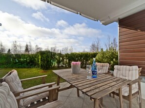 Une terrasse extérieure avec des meubles en bois, une bouteille d’eau et un verre.