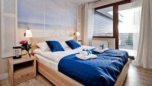 A modern bedroom with a large bed, wooden headboard, and a view of the outdoors through a window.