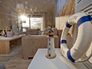 A cozy room with a white table, a small lighthouse model, and a lifebuoy with "WELCOME ABOARD" text. - BlueApart Apartamenty Na Klifie (Wladyslawowo)