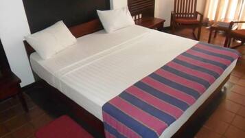 A hotel room with a large bed, wooden headboard, and a red bench.