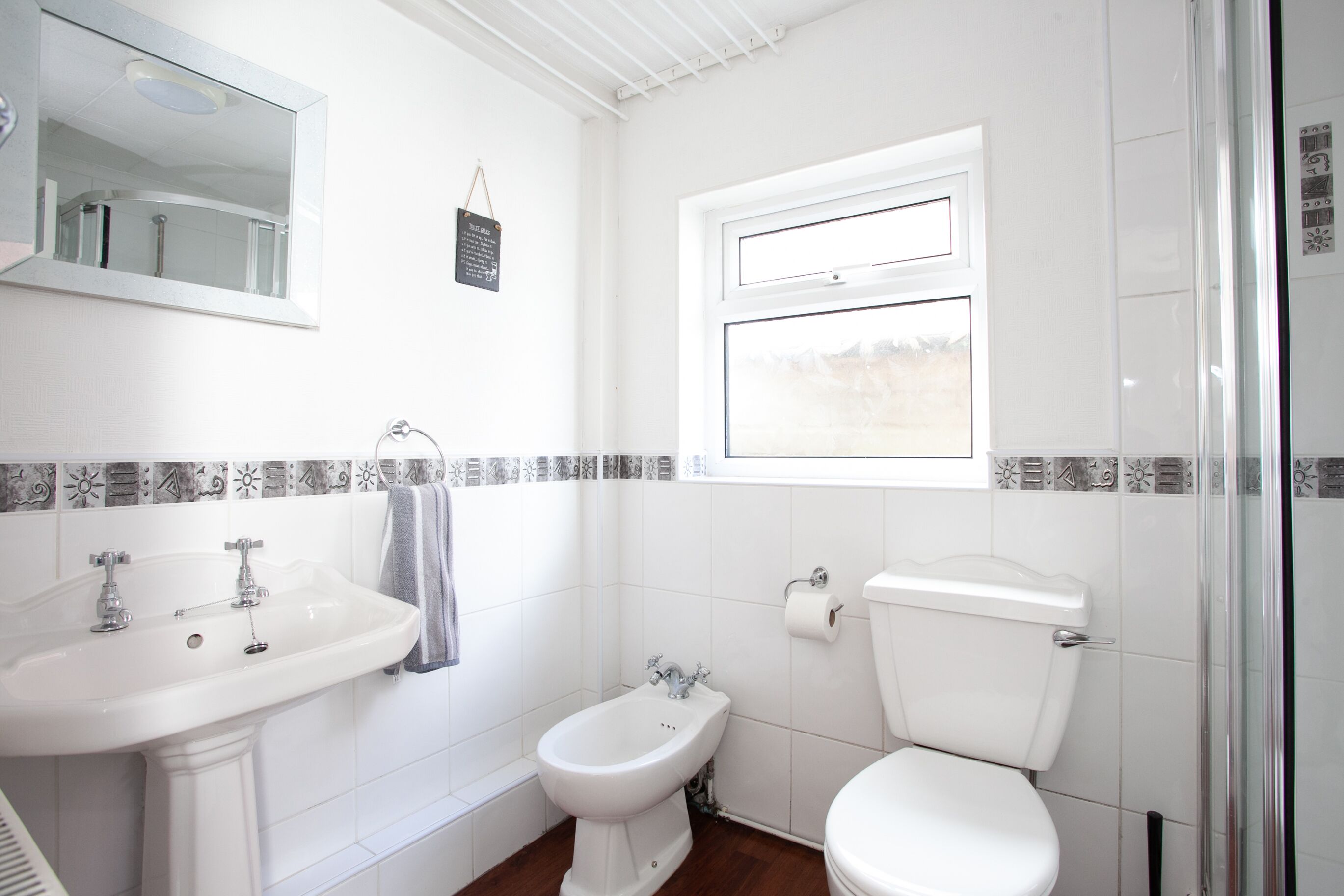 A bathroom with a sink, bidet, toilet, and a window.