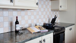 A kitchen with a wine bottle, a glass, and a book on the counter. - Spacious 3 bedroom Cottage in Whalley (Whalley)