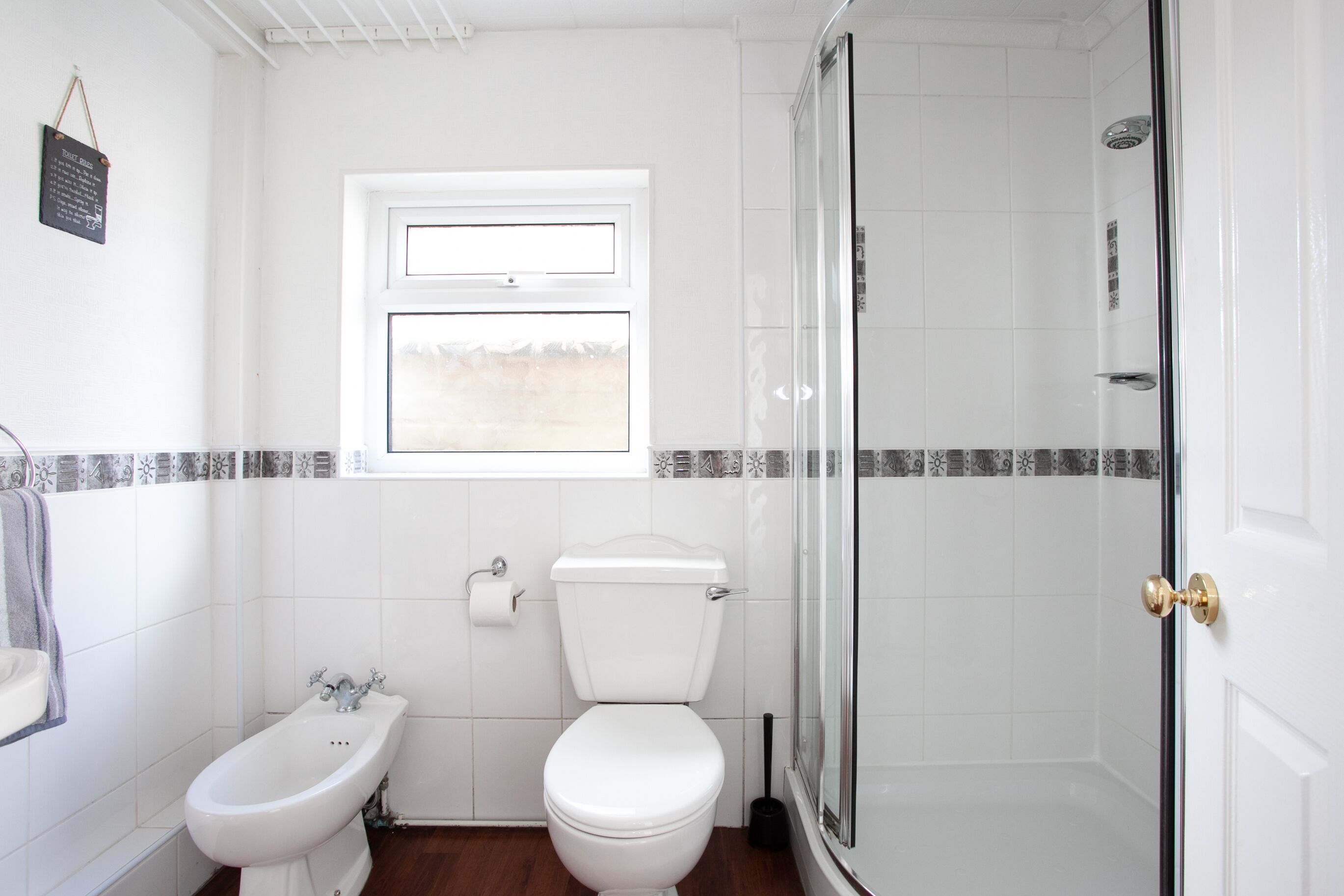 A bathroom with a bidet, toilet, and a glass-enclosed shower.