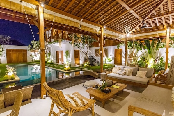 Relax by the pool surrounded by lush greenery and a serene atmosphere.