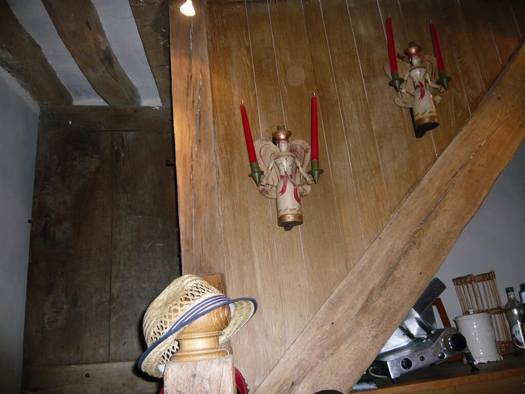 A wooden interior with a staircase, a decorative hat, and a shelf with bottles.