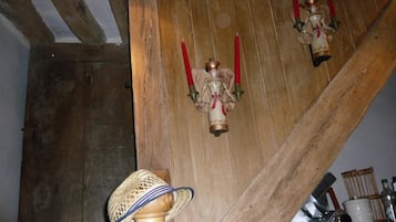 A wooden interior with a staircase, a decorative hat, and a shelf with bottles.