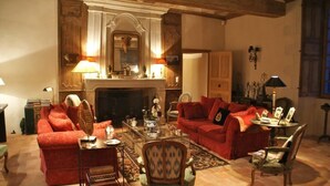 A cozy living room with a fireplace, red sofas, and a coffee table. - Chambres d'hôtes Logis de la Juquaise (Bierné-les-Villages)