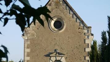 En lille, stenhus kirke med et kors på taget, et rundt vindue og en enkel indgang.