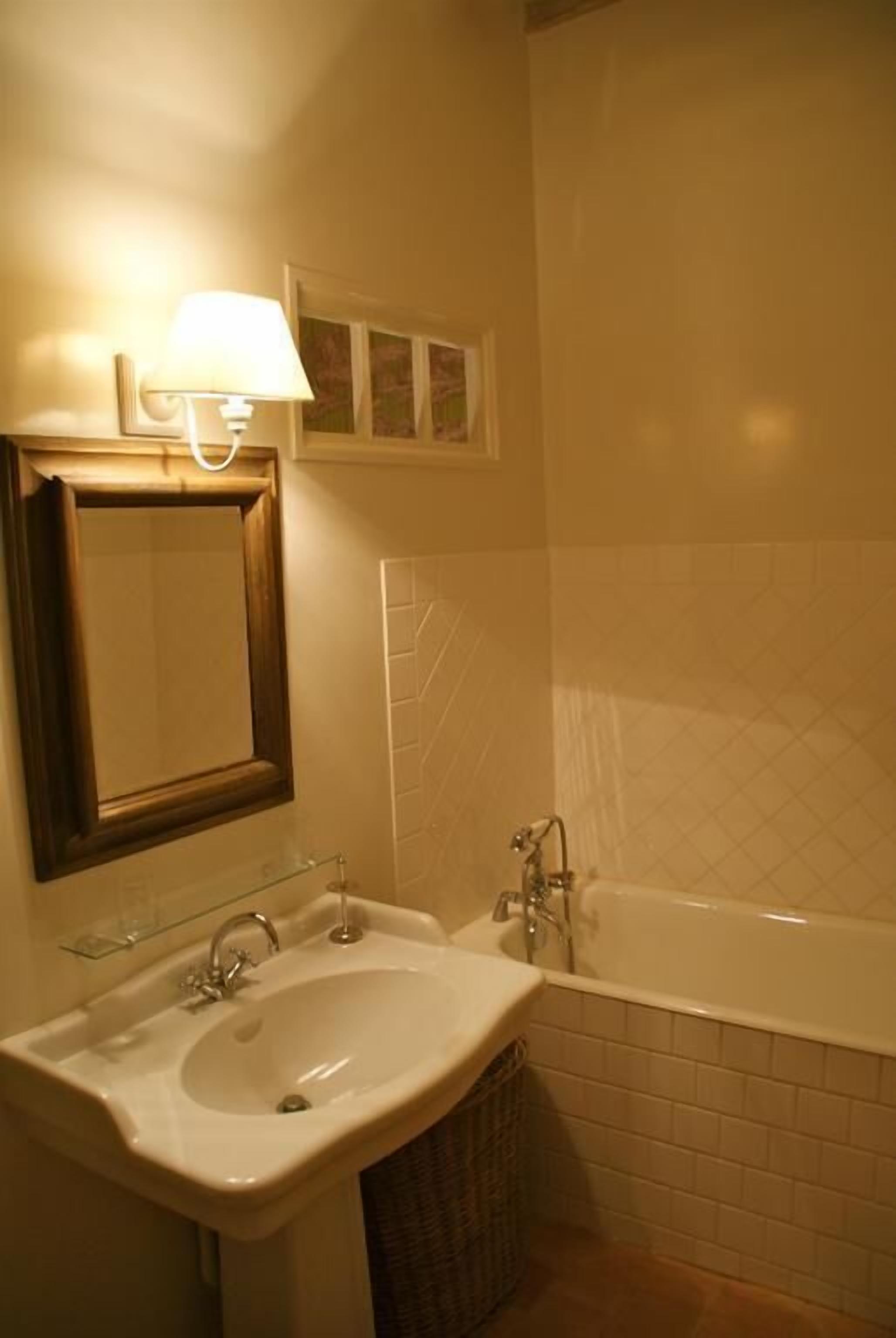 Une salle de bain avec un lavabo, un miroir et une baignoire.