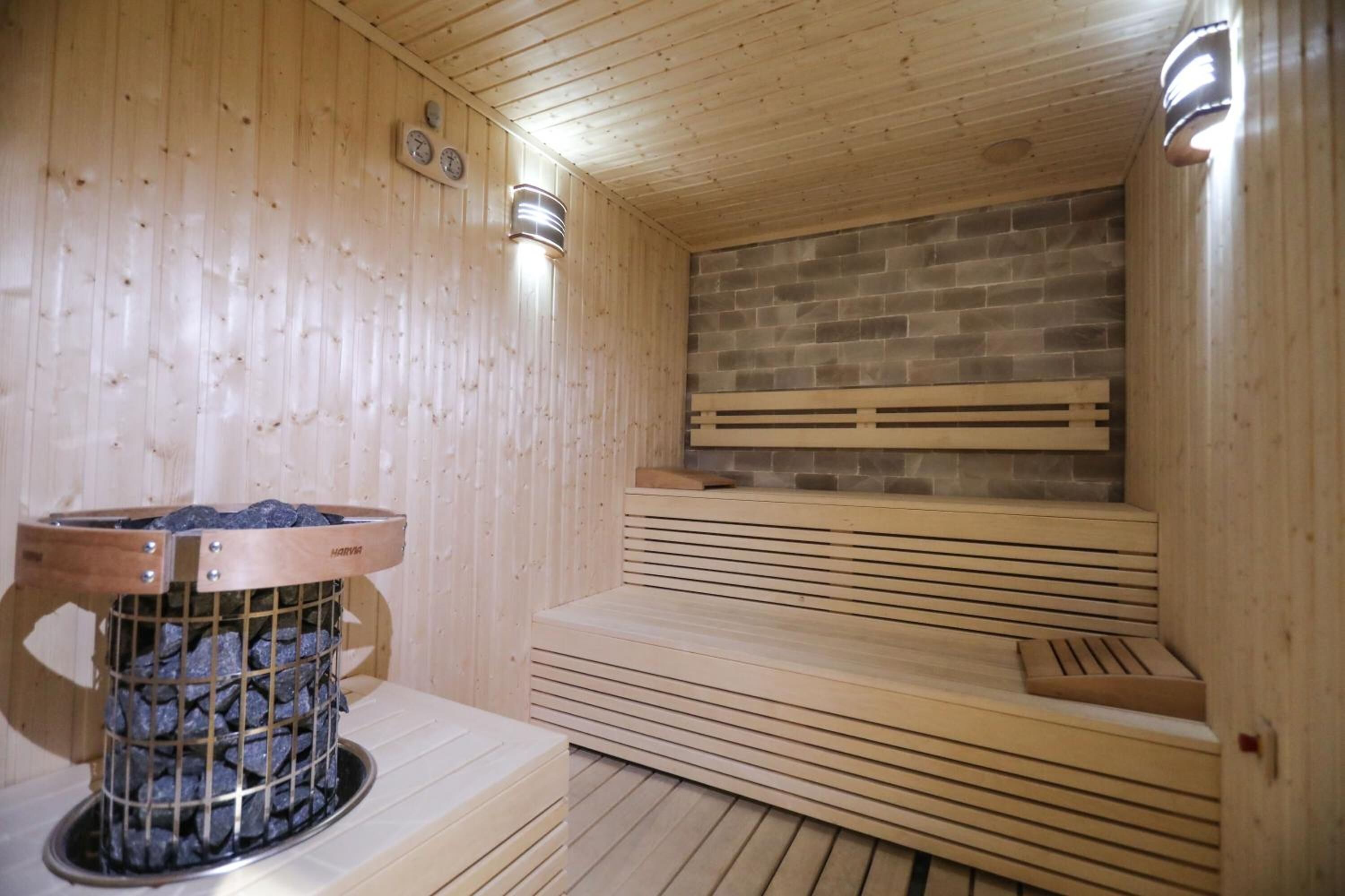 A sauna with wooden benches and a brick wall.