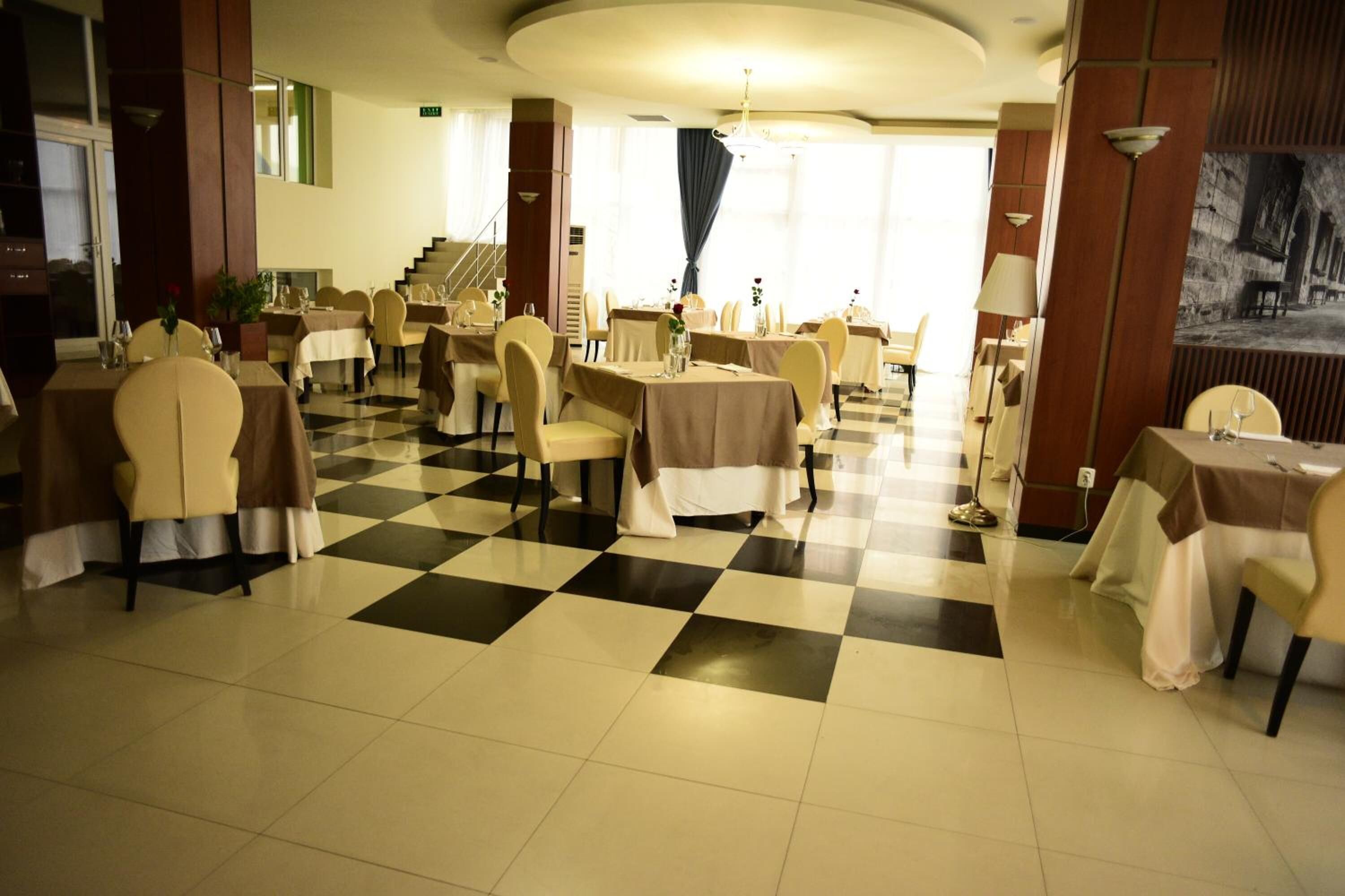 A dining area with checkered flooring, round tables, and chairs.