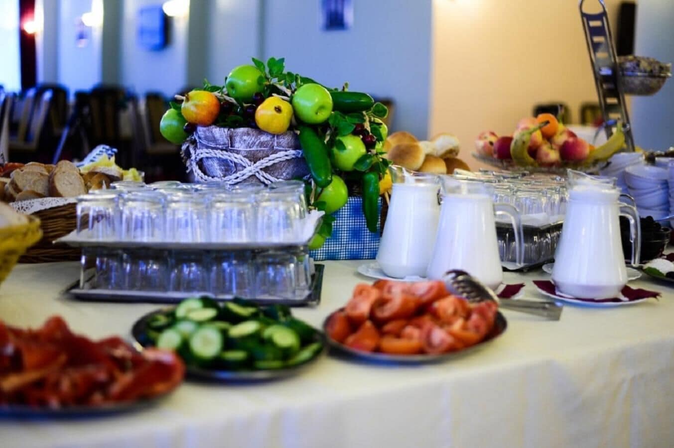 A buffet table with various food items, including fruits, vegetables, and a pitcher of milk.