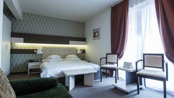 Une chambre d’hôtel comprenant un lit, un bureau, une chaise, un banc et un canapé.