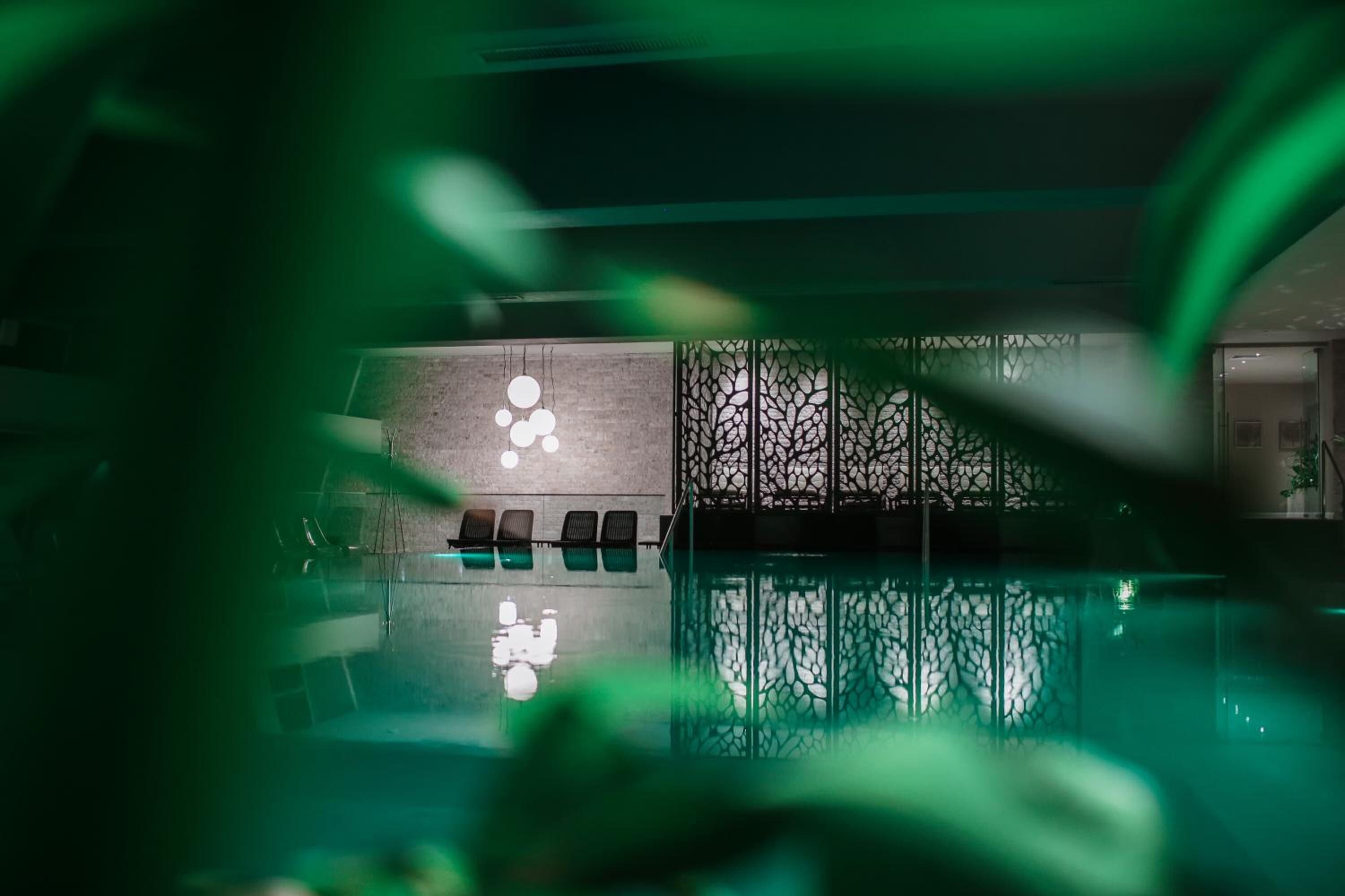A modern indoor pool area with a seating area and a decorative wall.