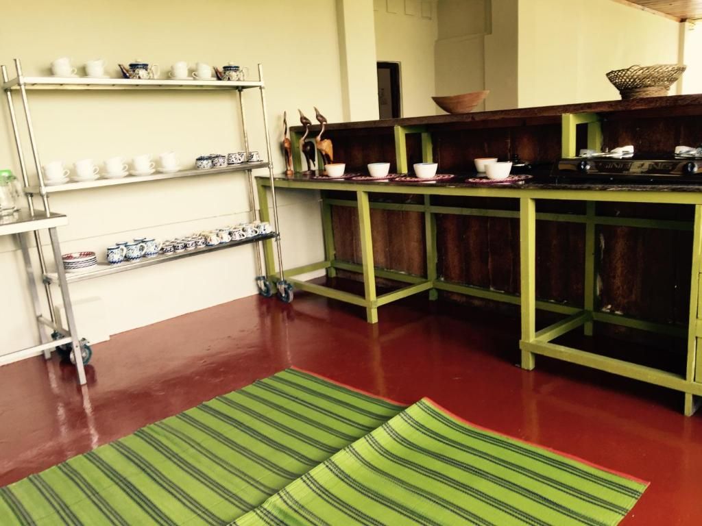 Une cuisine avec un plan de travail vert, des étagères où sont disposés de la vaisselle blanche et à motifs, et un tapis vert à rayures sur le sol.