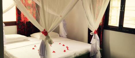 A room with a bed under a white canopy, a patterned rug, and a window with curtains.