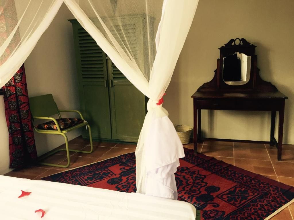 A room with a bed, a chair, a table, and a mirror.