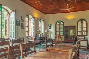 Una habitació àmplia amb mobiliari de fusta, grans finestres d'arc i un ventilador de sostre.
