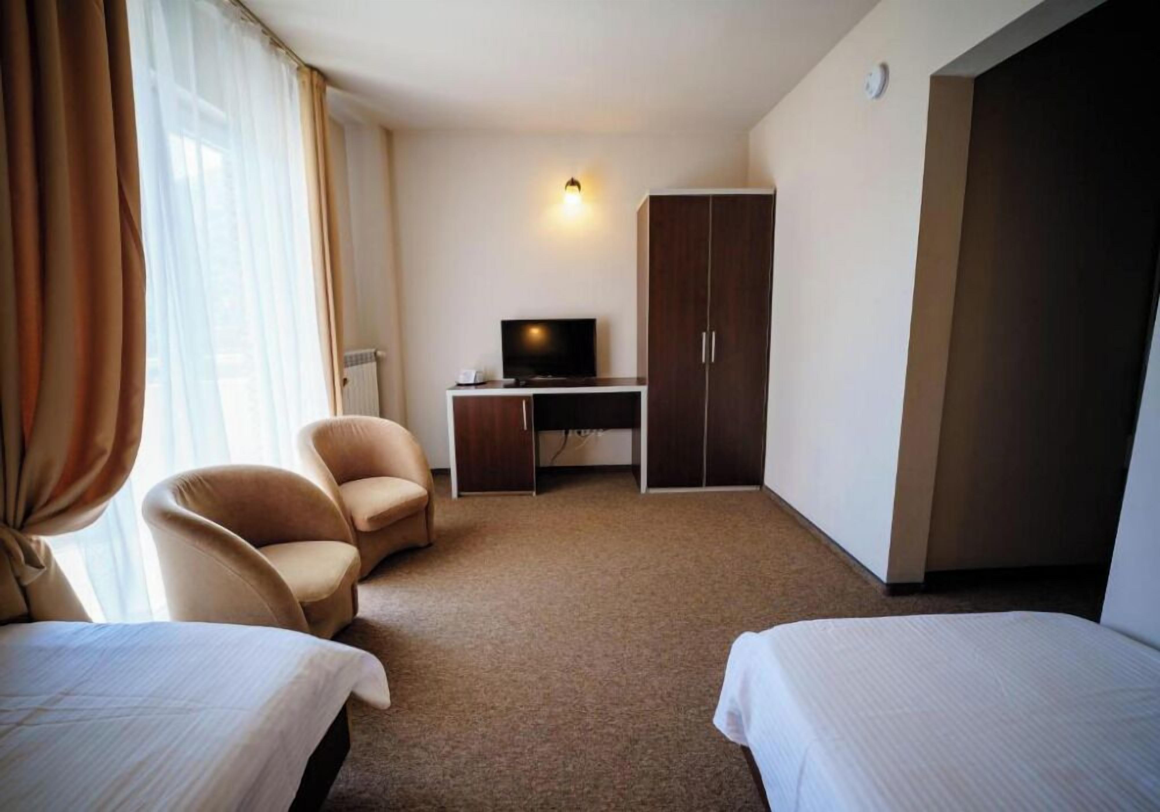 Ett hotellrum med två sängar, ett skrivbord med en tv, en garderob och en stol.