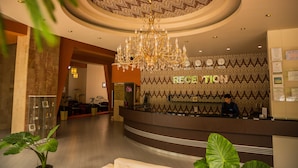 A reception area with a chandelier, a reception desk, and a patterned wall with the word "RECEPTION" on it. - Diana Resort (Baile Herculane)