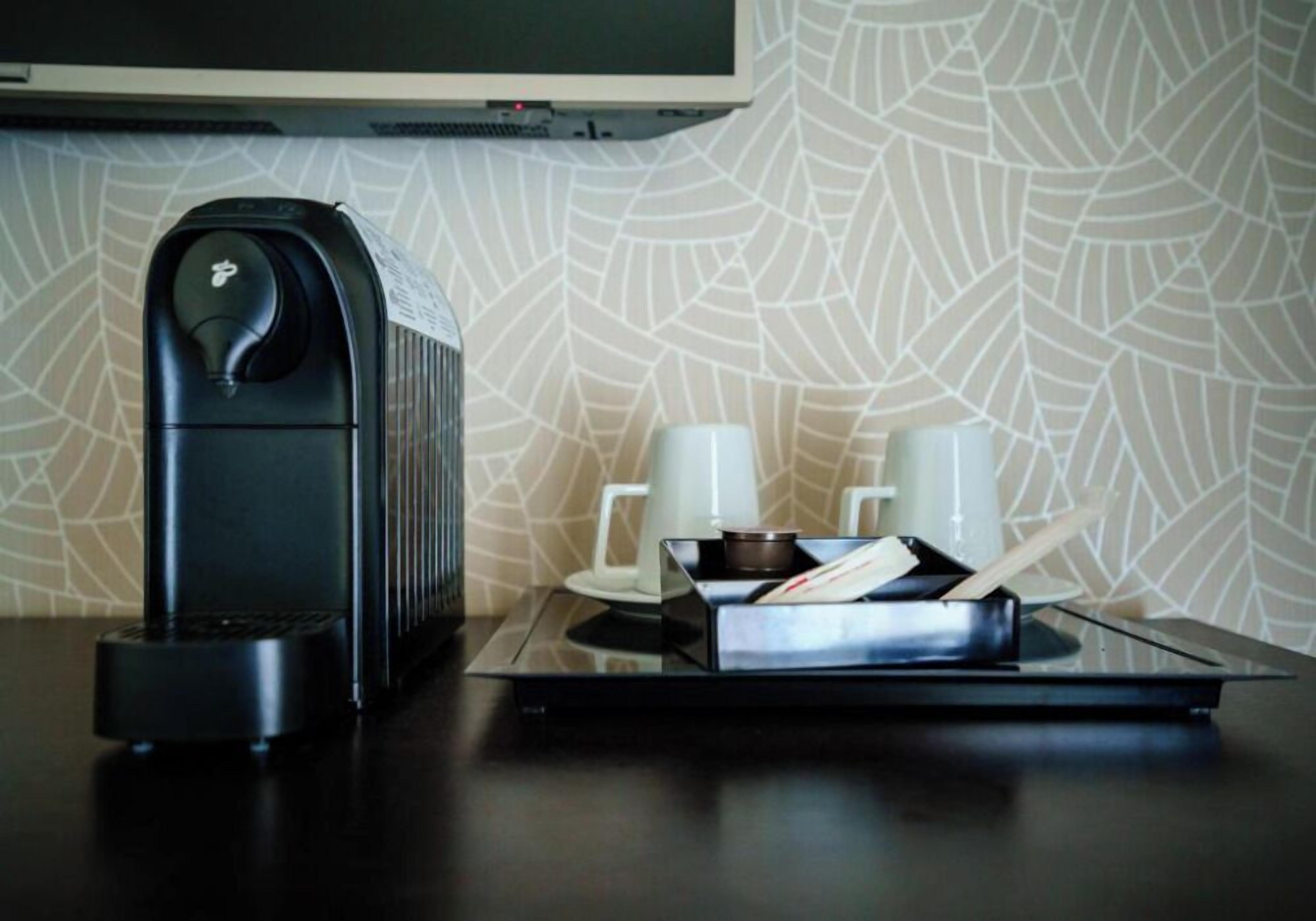 A coffee machine, a tray with a cup and saucer, and a small bowl on a table.