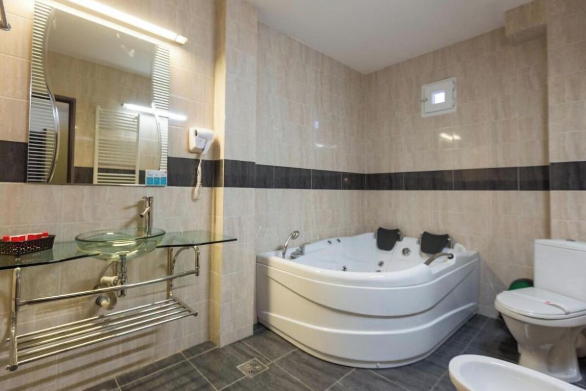 A bathroom with a glass sink, a white bathtub, and a toilet.