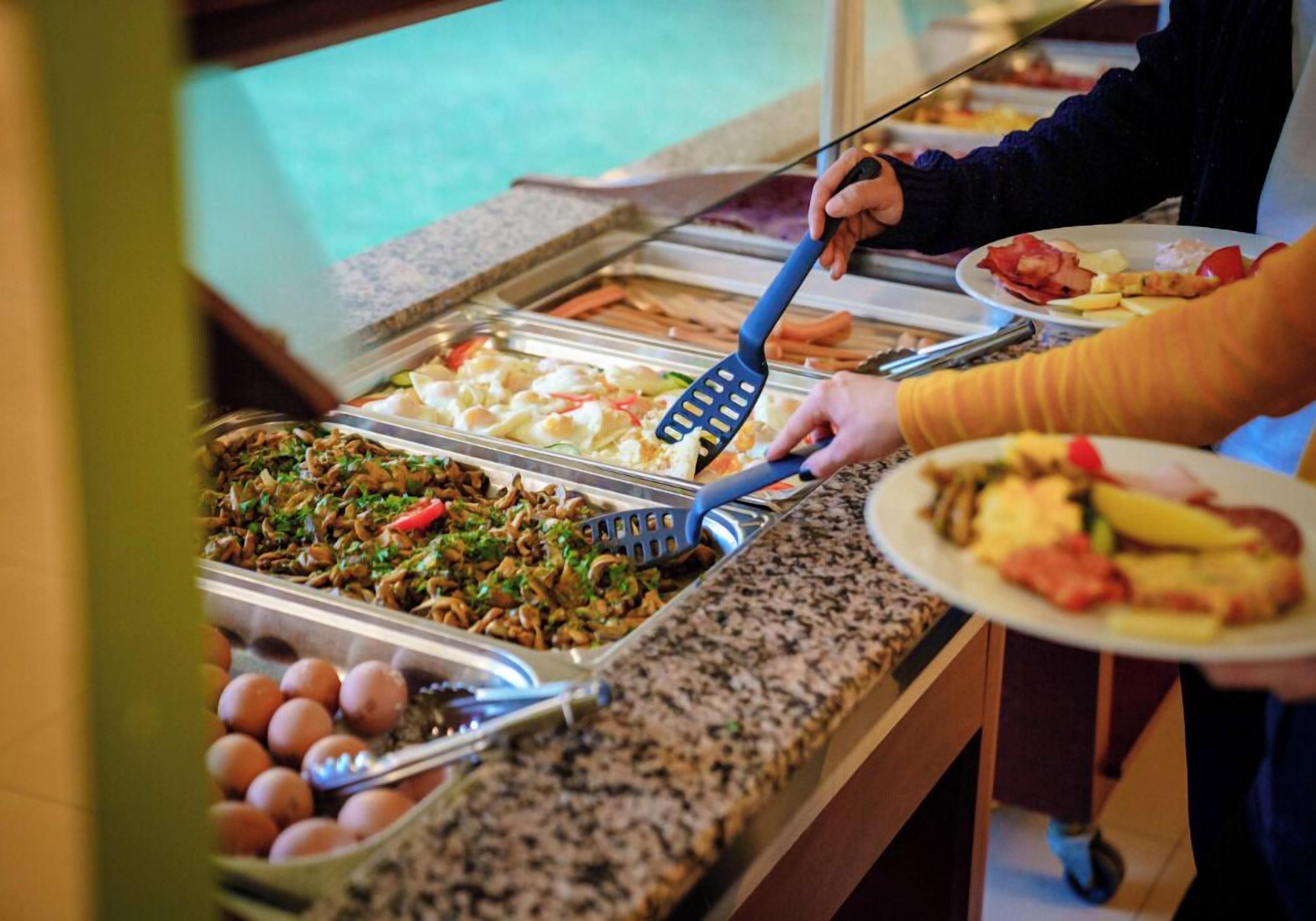 Un buffet proposant une variété de plats et une personne utilisant une spatule.