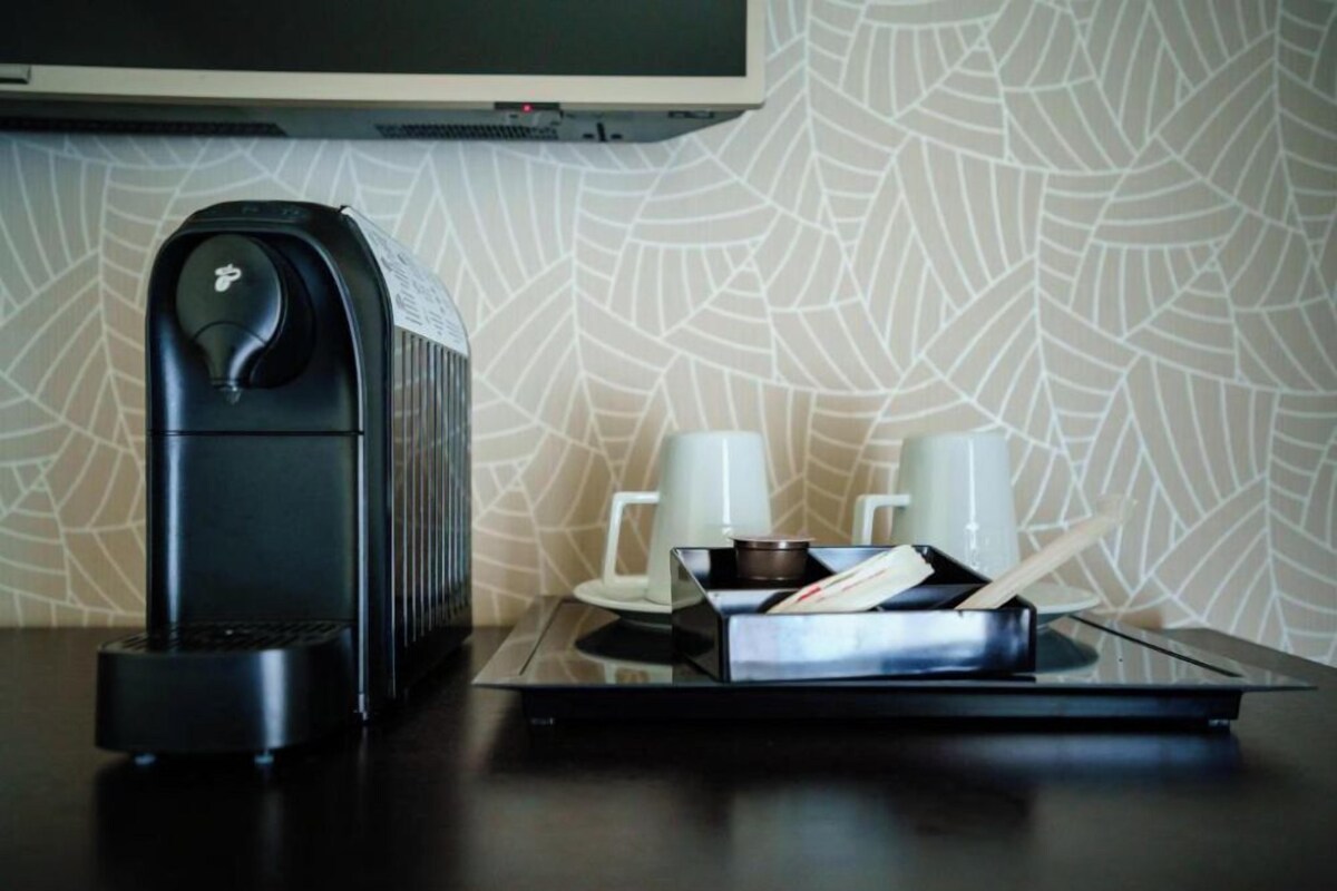 A coffee machine, a tray with a cup and saucer, and a small bowl on a table.