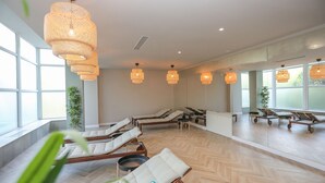 A spa room with wooden flooring, multiple lounge chairs, and large windows providing natural light. - Diana Resort (Baile Herculane)