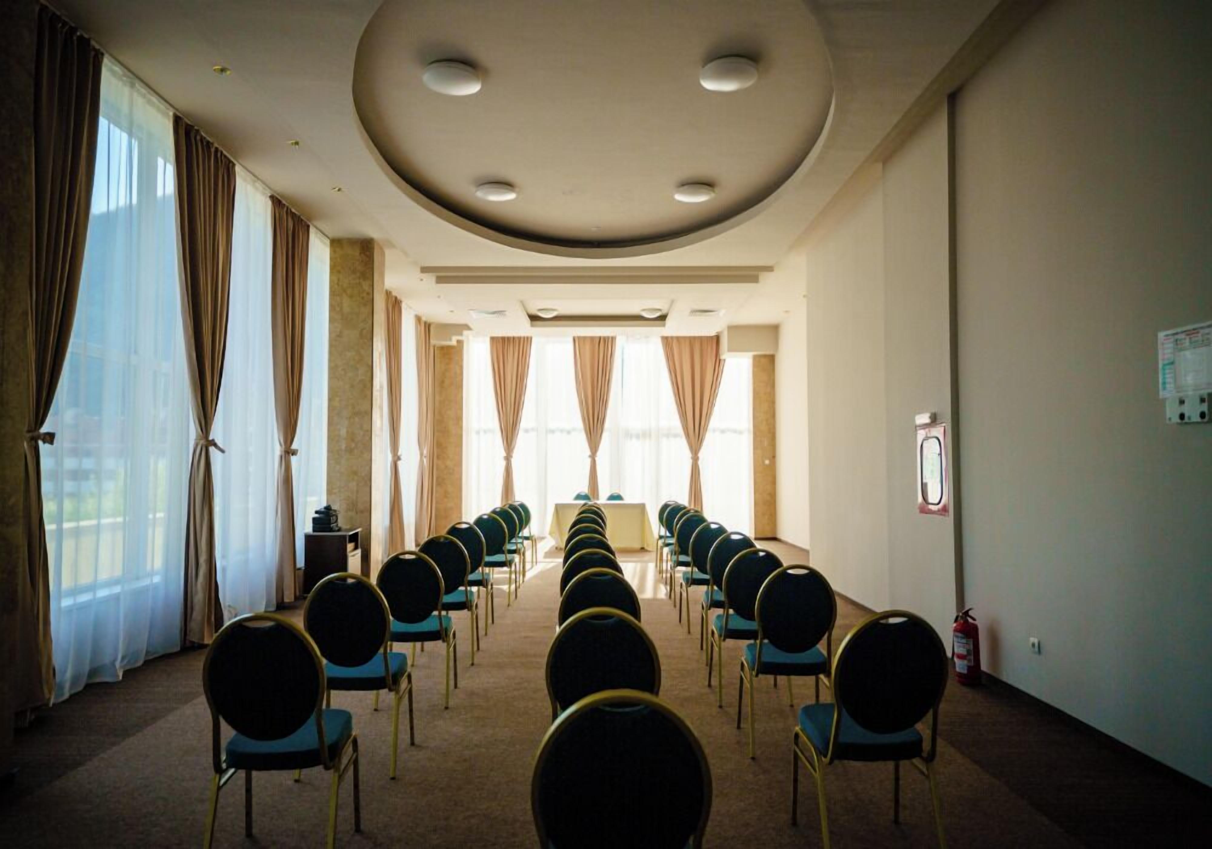 A conference room with rows of chairs, a table, and a fire extinguisher on the wall.