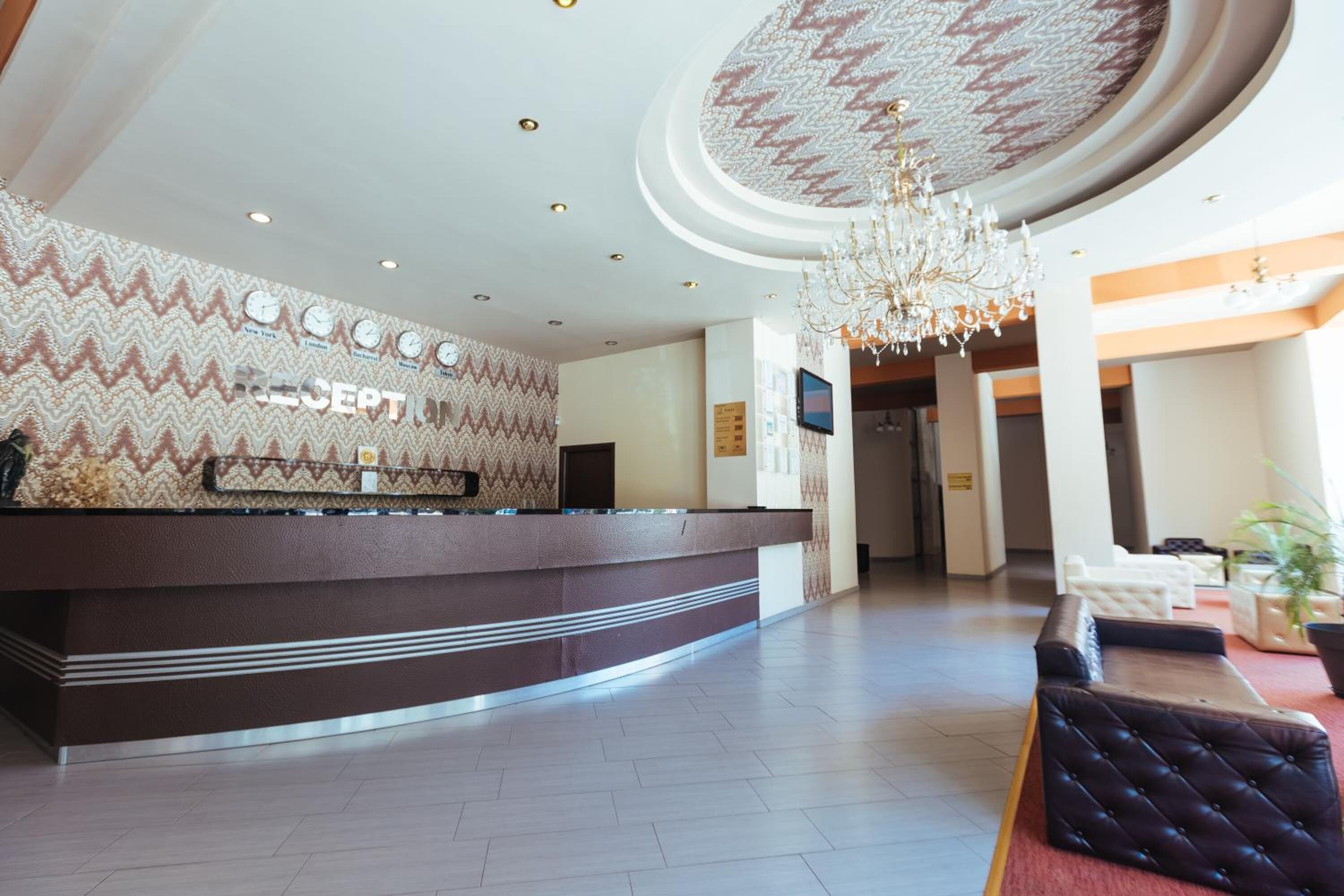 Een hotel receptie met een behang, een receptiebalie, een kroonluchter en een zithoek.