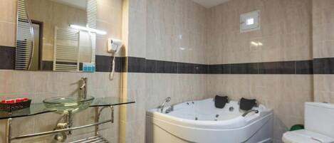 A bathroom with a glass sink, a white bathtub, and a toilet.