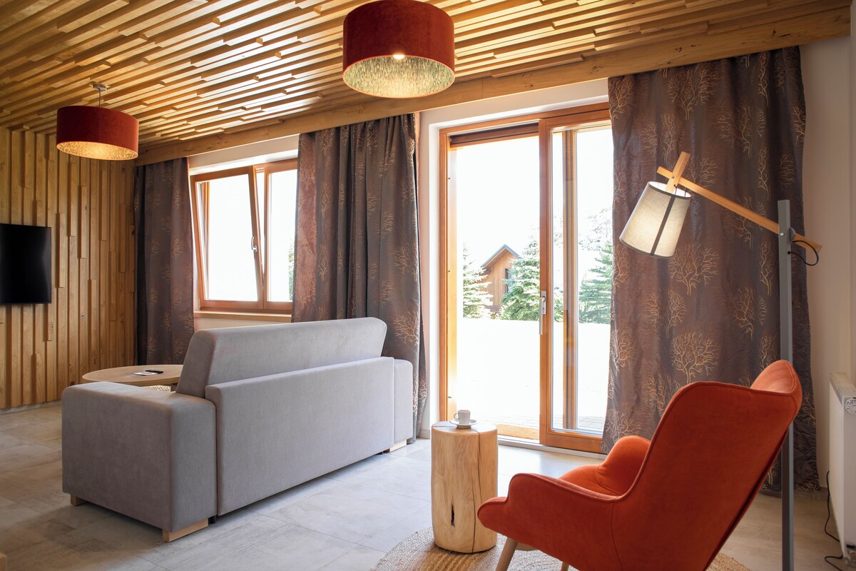 A modern living room with a sofa, a chair, a lamp, and a television.