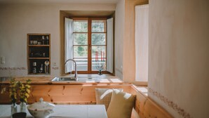 A cozy kitchen with wooden furniture, a sink, and a window with curtains. - Warm vacation apartment at Hof Neuhaus (Platzers)