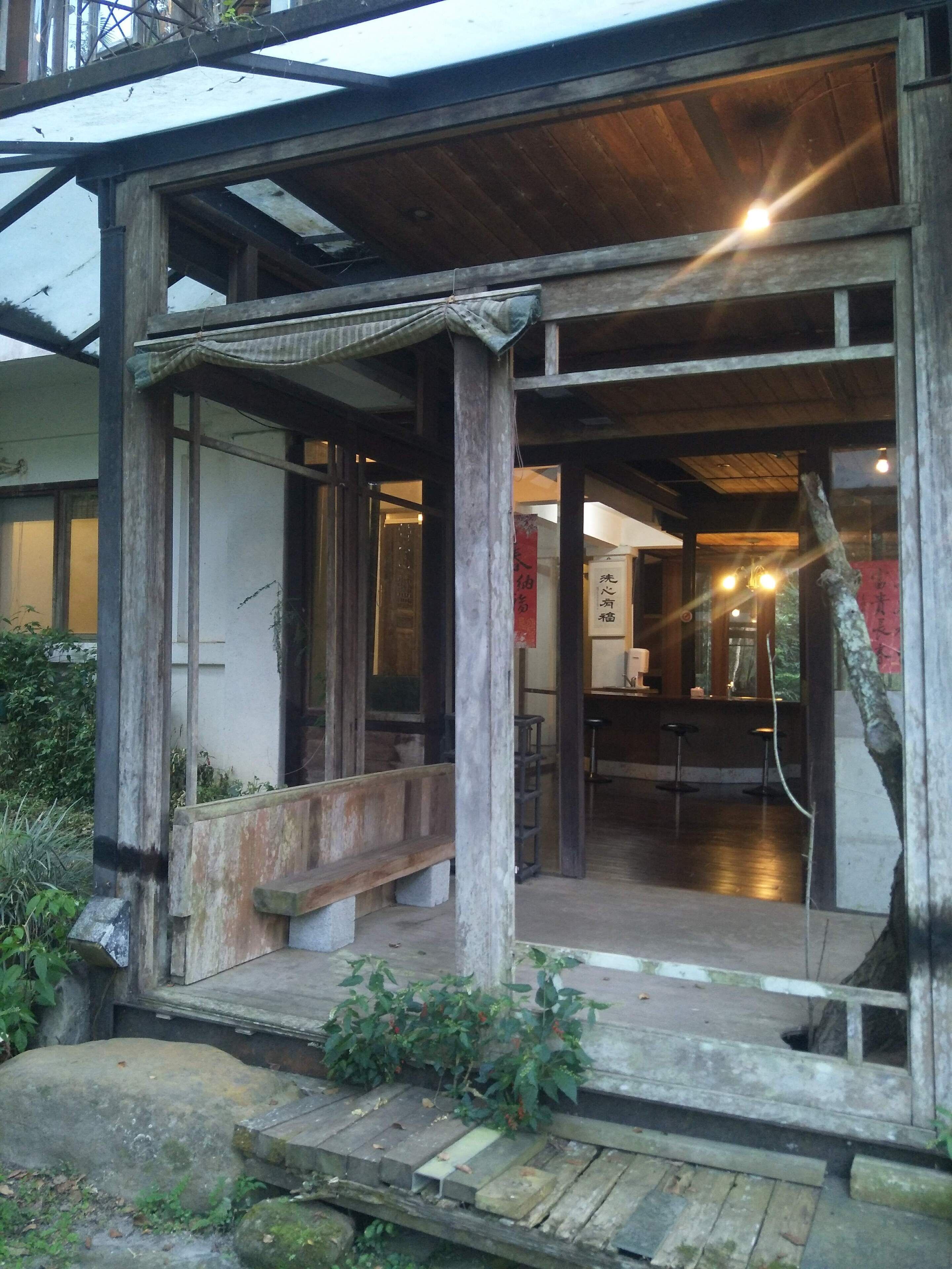 A traditional wooden building with a covered entrance, stone steps, and a bench.