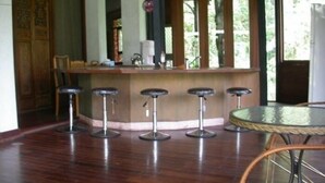 A bar area with a wooden counter, four stools, and a round table. - Water Home (Puli)
