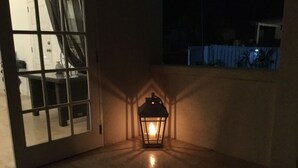 A room with a large window, a door, and a lit lantern in the corner. - Private detached villa in a quiet location close to the sea and beaches (Porters)
