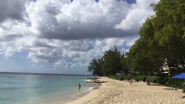 A beach with clear turquoise water, sandy shore, and lush green trees. - Private detached villa in a quiet location close to the sea and beaches (Porters)