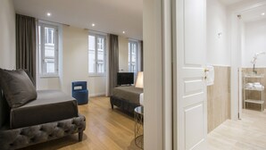 Een moderne hotelkamer met een bed, een televisie, een bureau en een badkamer met douche en handdoekrek.