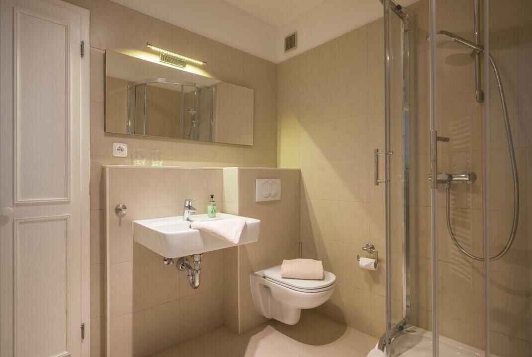 A compact bathroom with a sink, toilet, and glass-enclosed shower.