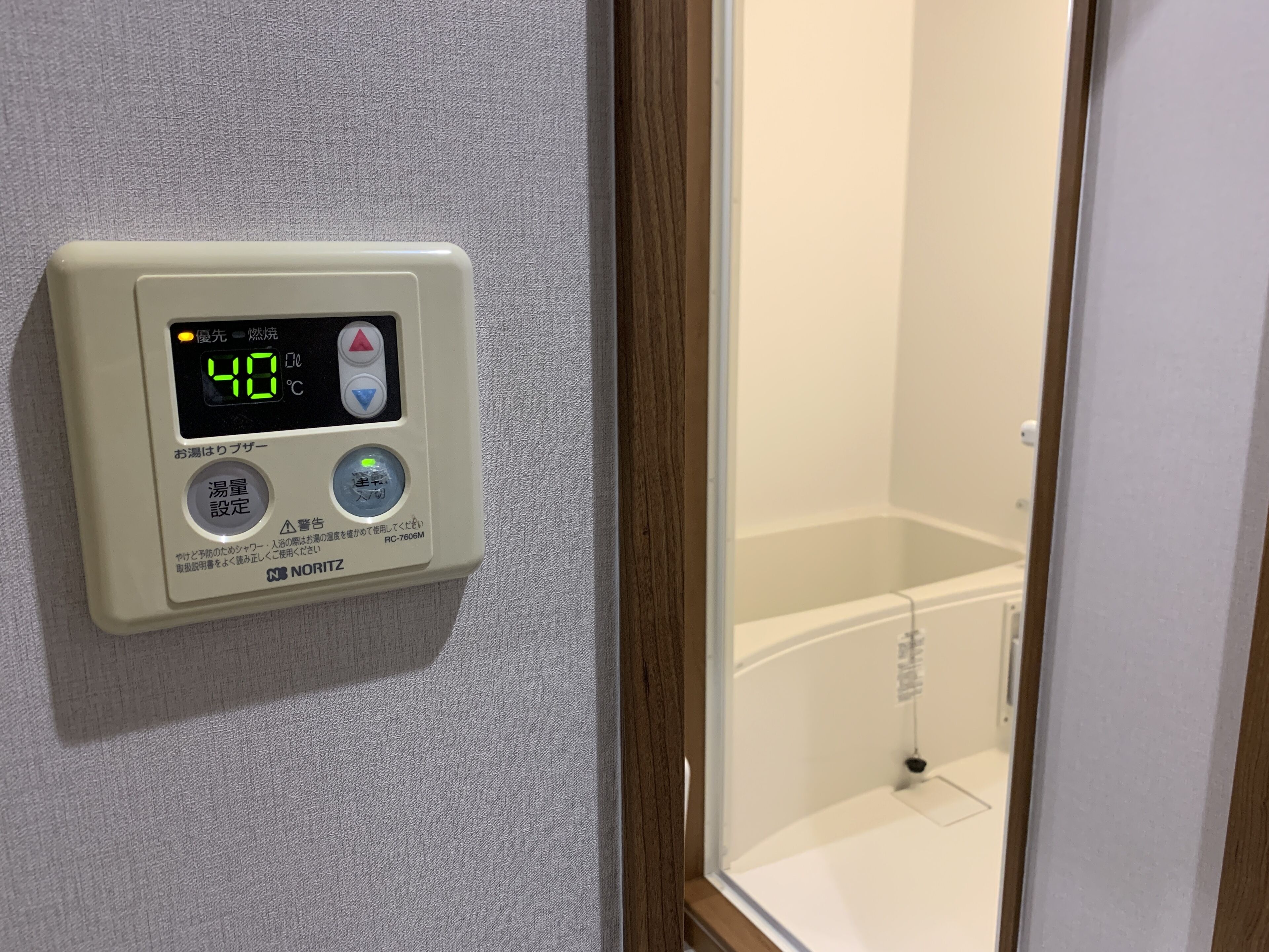 A digital thermostat with temperature settings and control buttons, mounted on a textured wall.