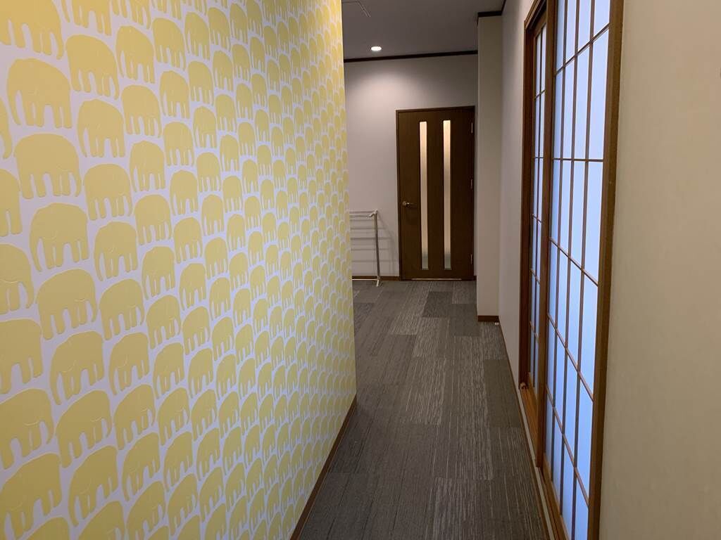 Un pasillo con papel tapiz estampado, una puerta de madera y una ventana con diseño de cuadrícula.
